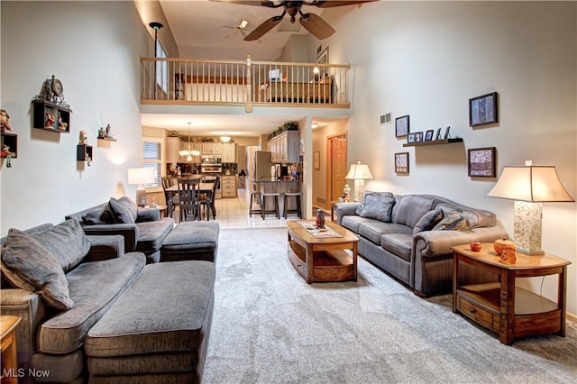 living room featuring ceiling fan, carpet, and a high ceiling