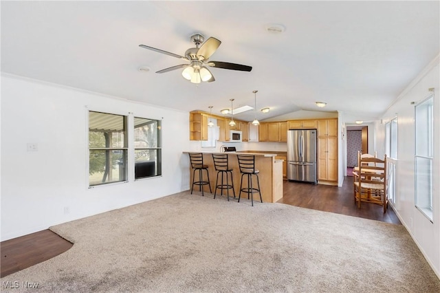 kitchen featuring stainless steel refrigerator, lofted ceiling, a kitchen breakfast bar, hanging light fixtures, and kitchen peninsula