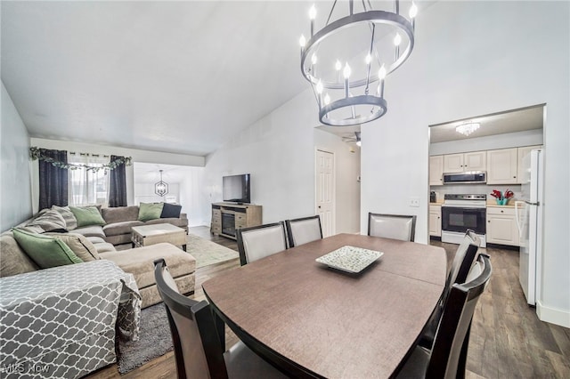 dining room featuring a fireplace, ceiling fan with notable chandelier, dark wood-type flooring, and high vaulted ceiling