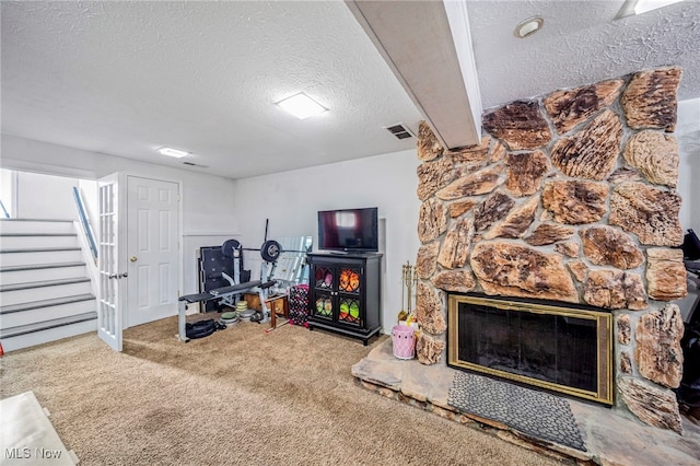 interior space with a stone fireplace, carpet floors, and a textured ceiling