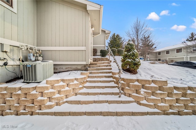 snow covered property with central AC unit