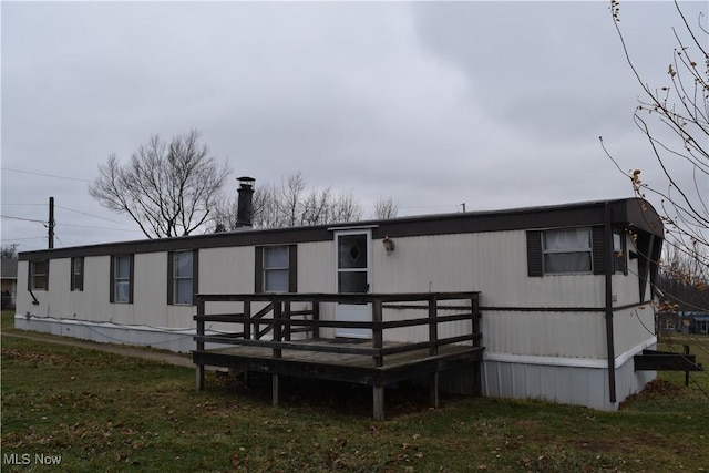 rear view of house with a wooden deck and a lawn