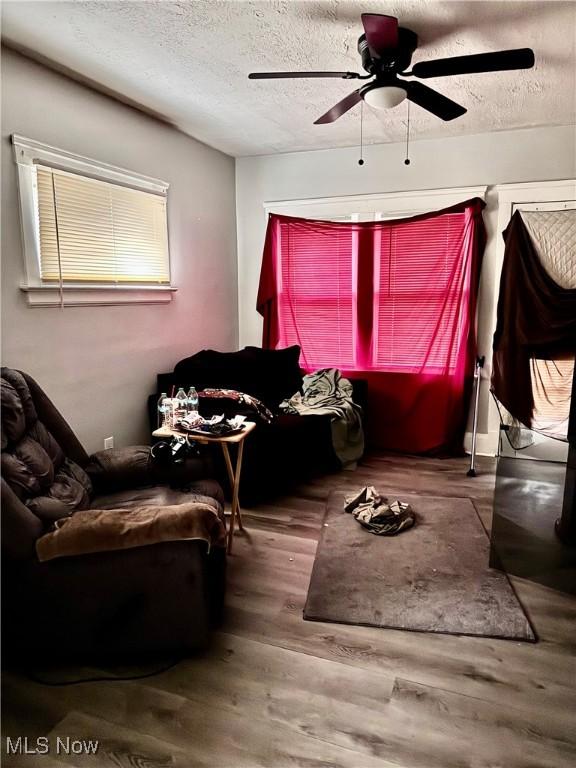 interior space with ceiling fan, wood-type flooring, and a textured ceiling