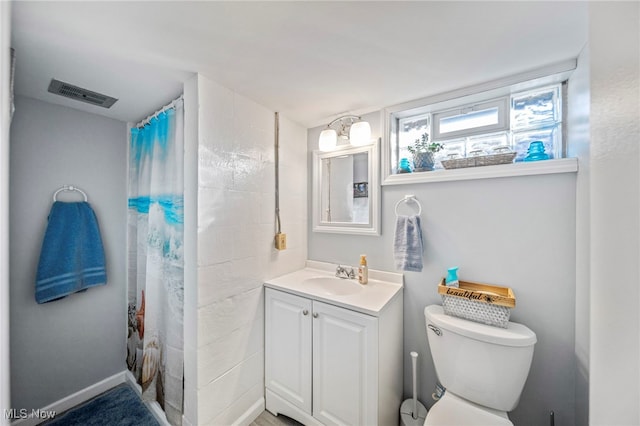 bathroom with walk in shower, vanity, and toilet