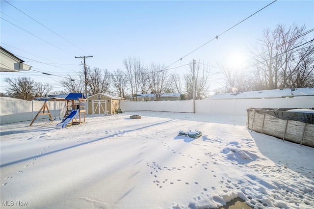 yard covered in snow featuring a storage unit and a playground