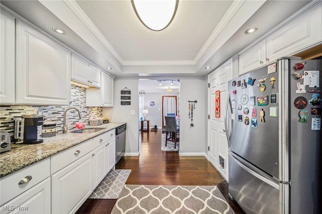 kitchen with appliances with stainless steel finishes, white cabinetry, sink, light stone counters, and a tray ceiling