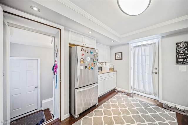 kitchen featuring white cabinetry, dark hardwood / wood-style flooring, crown molding, and stainless steel refrigerator