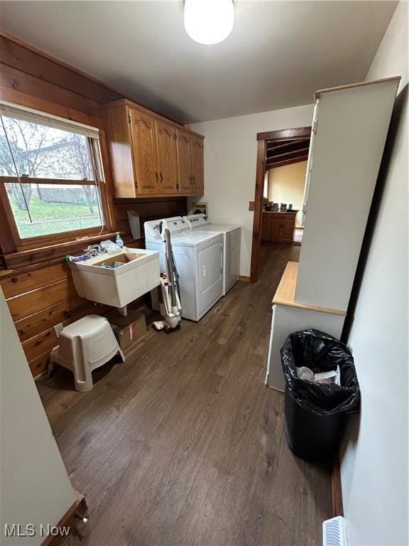 clothes washing area with sink, wooden walls, cabinets, dark hardwood / wood-style floors, and independent washer and dryer