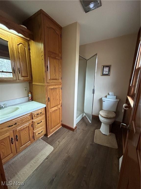 bathroom featuring vanity, hardwood / wood-style flooring, a shower with shower door, and toilet