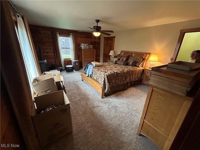 bedroom featuring wooden walls, ceiling fan, and carpet flooring