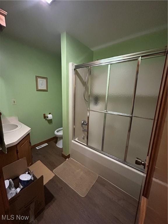 full bathroom with hardwood / wood-style flooring, enclosed tub / shower combo, vanity, and toilet