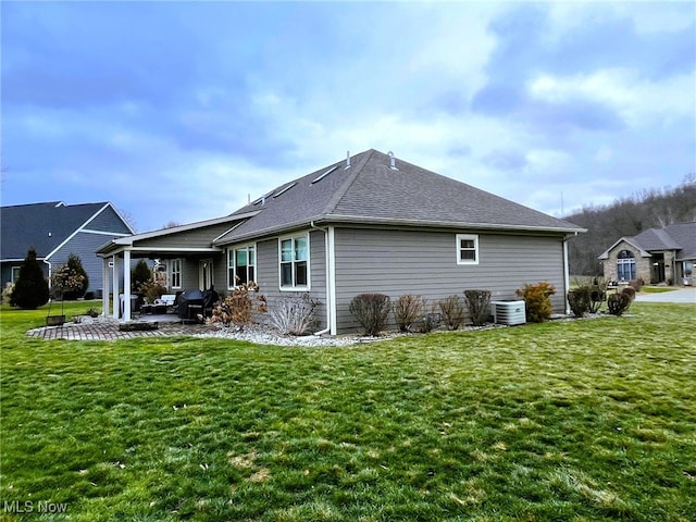 rear view of property with a lawn, central air condition unit, and a patio area