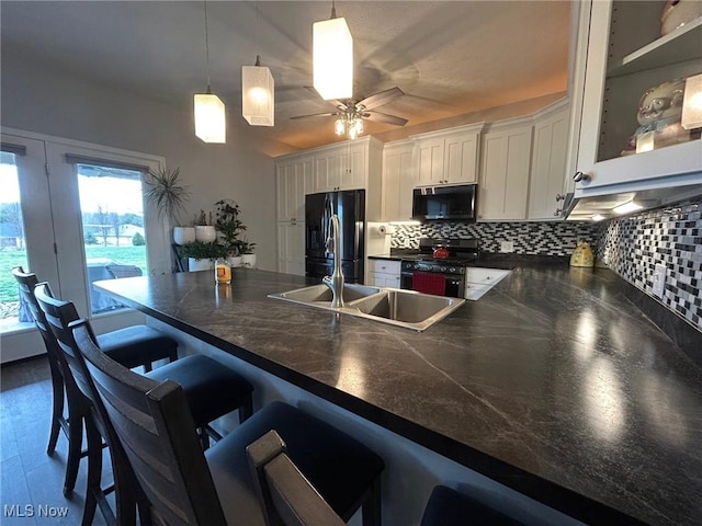 kitchen with a breakfast bar, white cabinetry, hanging light fixtures, black appliances, and decorative backsplash