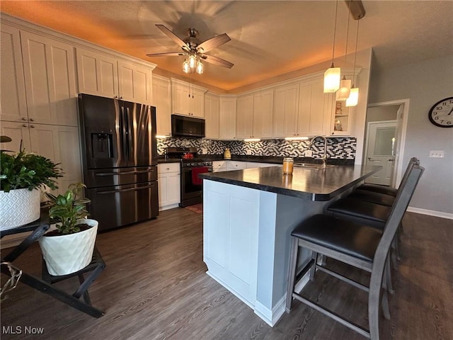 kitchen featuring stainless steel gas stove, white cabinets, a kitchen breakfast bar, hanging light fixtures, and fridge with ice dispenser