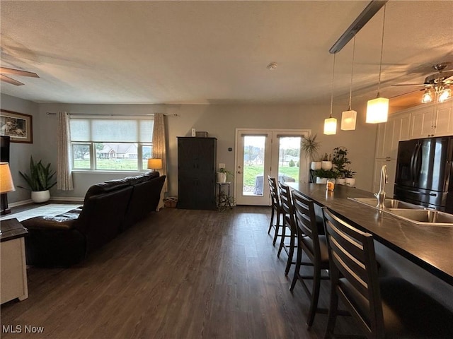 interior space featuring black refrigerator, hanging light fixtures, white cabinetry, and ceiling fan