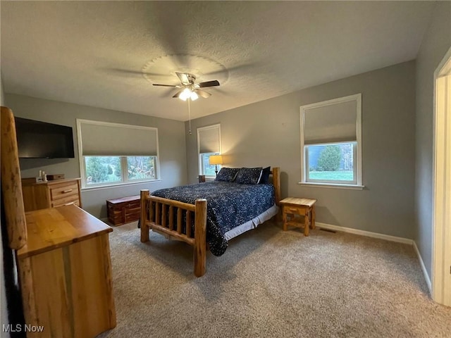 bedroom featuring ceiling fan, carpet floors, multiple windows, and a textured ceiling