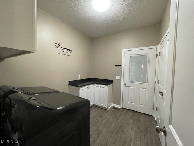 clothes washing area featuring cabinets, dark hardwood / wood-style flooring, a textured ceiling, and independent washer and dryer