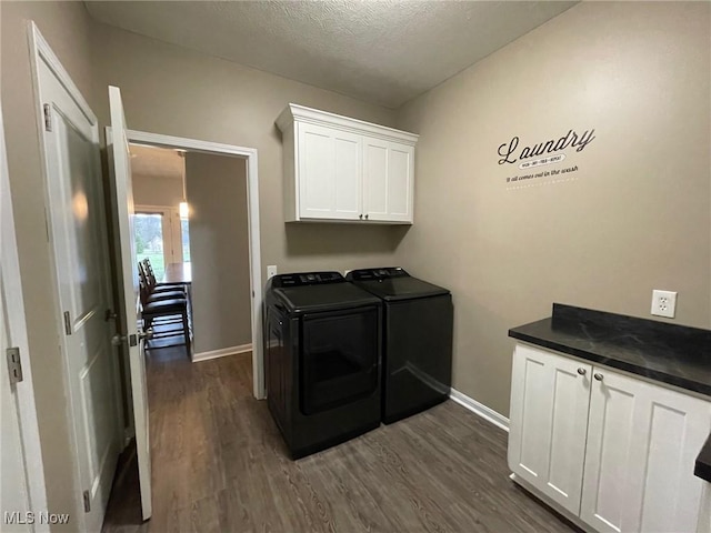 laundry room with dark wood-type flooring, cabinets, separate washer and dryer, and a textured ceiling