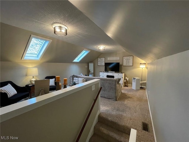 carpeted bedroom with lofted ceiling with skylight and a textured ceiling