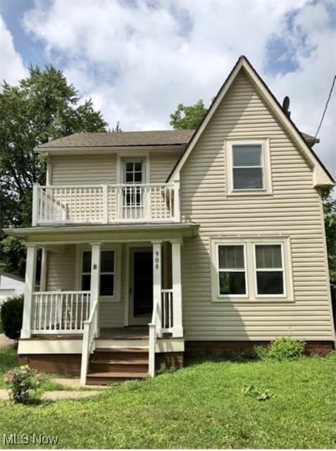 back of house with a yard, a balcony, and covered porch