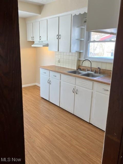 kitchen featuring tasteful backsplash, sink, white cabinets, and light hardwood / wood-style flooring