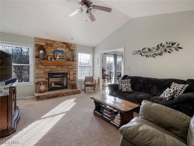 carpeted living room featuring a stone fireplace, lofted ceiling, and ceiling fan