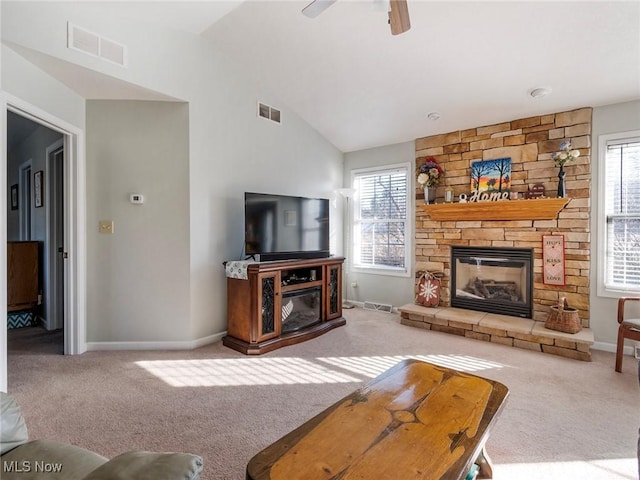 living room featuring ceiling fan, light colored carpet, a stone fireplace, and vaulted ceiling