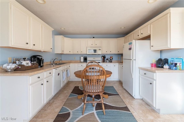 kitchen with sink, white appliances, white cabinets, and light tile patterned flooring