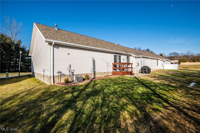 back of property with central AC unit, a lawn, and a deck