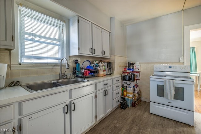 kitchen featuring white electric range oven, sink, white cabinetry, tile walls, and hardwood / wood-style floors