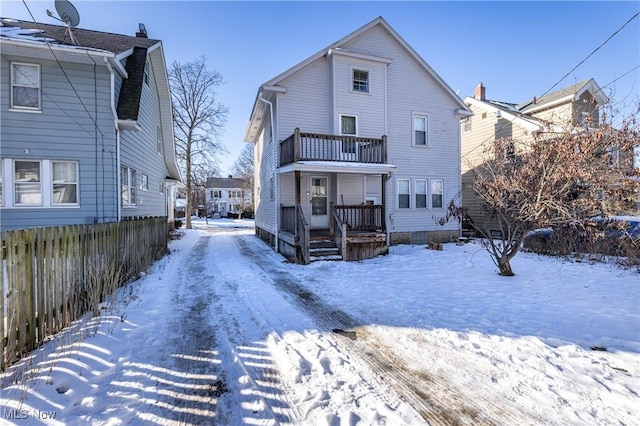 snow covered house featuring a balcony