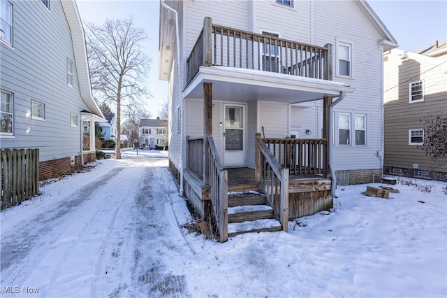 snow covered rear of property with a balcony