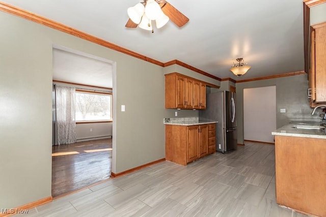 kitchen with sink, light wood-type flooring, stainless steel refrigerator, ornamental molding, and ceiling fan