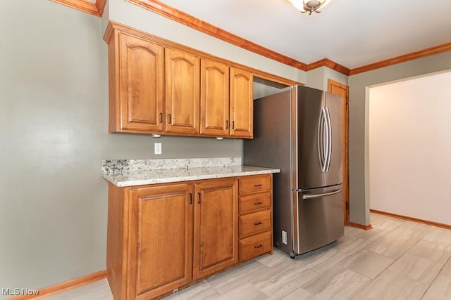 kitchen featuring ornamental molding, stainless steel fridge, and light stone countertops