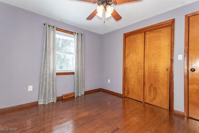 unfurnished bedroom with dark wood-type flooring, ceiling fan, and a closet