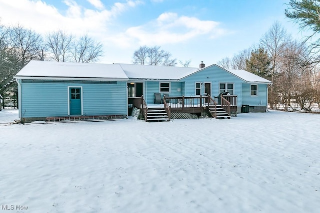 snow covered back of property featuring a deck