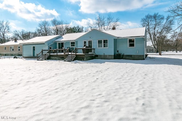 snow covered house with a deck and central air condition unit