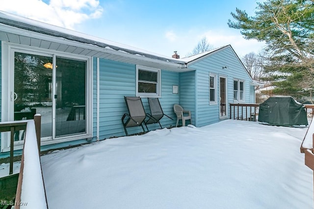 snow covered rear of property with a deck