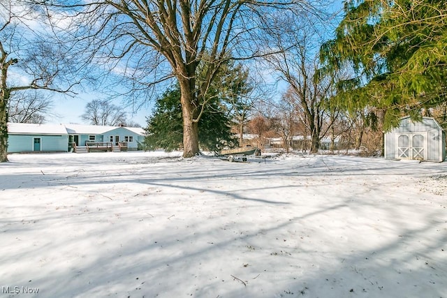 yard covered in snow featuring a wooden deck and a storage shed