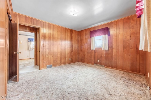 carpeted spare room with wooden walls