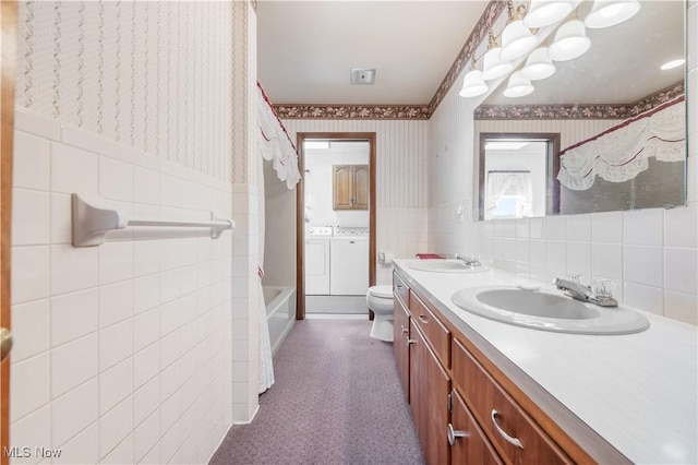 full bathroom with tile walls, vanity, independent washer and dryer,  shower combination, and toilet