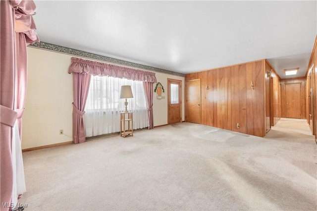 empty room with light colored carpet and wood walls