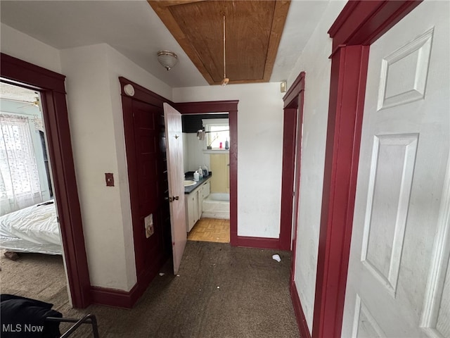 hallway featuring a wealth of natural light and dark colored carpet