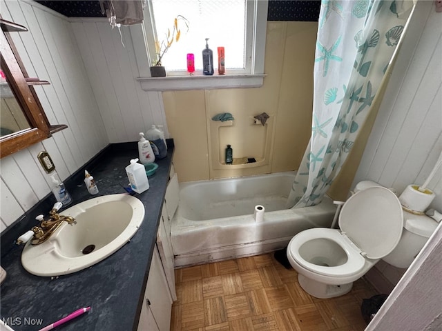 full bathroom with shower / tub combo, wooden walls, vanity, parquet flooring, and toilet