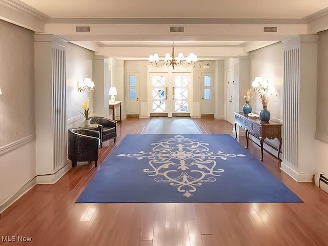 entrance foyer with ornamental molding, hardwood / wood-style floors, and a chandelier