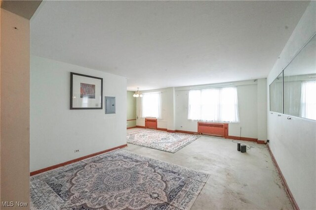 empty room with an inviting chandelier, electric panel, and radiator