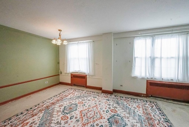 unfurnished room with radiator heating unit and a notable chandelier