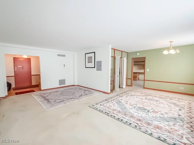 unfurnished room featuring concrete flooring, electric panel, and a chandelier