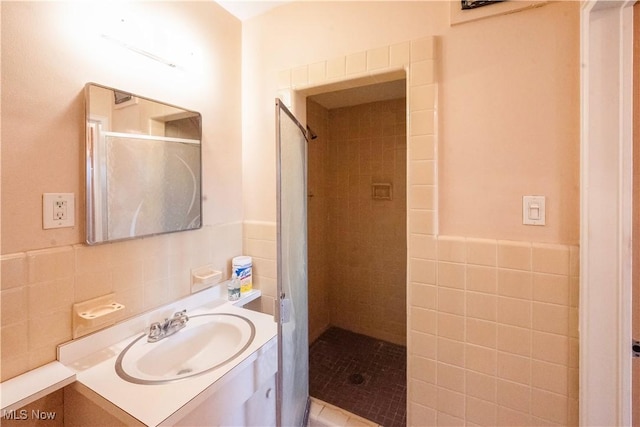 bathroom featuring vanity, tiled shower, and tile walls