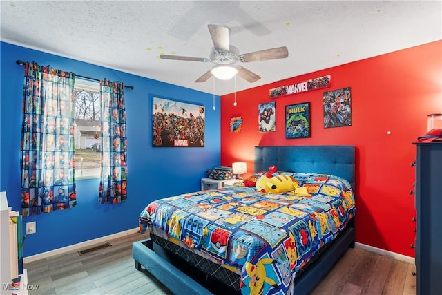 bedroom featuring ceiling fan, wood-type flooring, and a textured ceiling